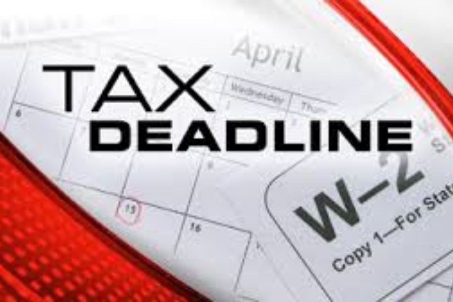 A W-2 tax form laying on top of a calendar open to April with Tax Deadline typed above it in red