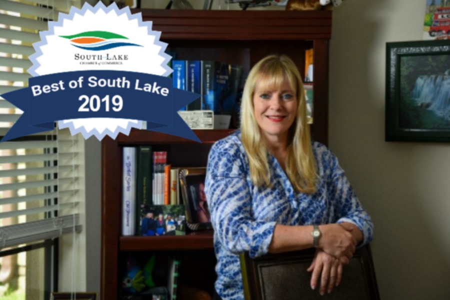 Denise Calderon smiling as she leans against a chair in her office in Minneola, Florida with a badge for Best of South Lake 2019 above her right should