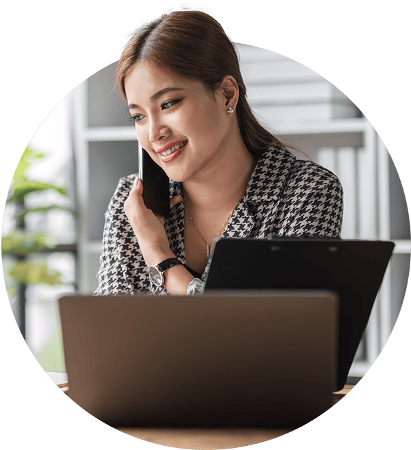 Business owner smiling as she is reviewing her financials at her desk while talking to her Certified Public Accountant on the phone